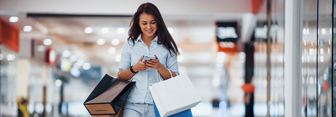 woman in the supermarket with many of packages and phone in hands have shopping day