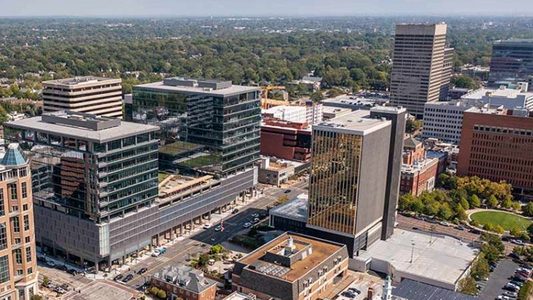 Aerial view of office building exterior along city street on a sunny day.