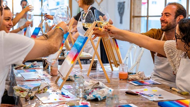 Friends toasting happily with glasses of wine in a painting workshop