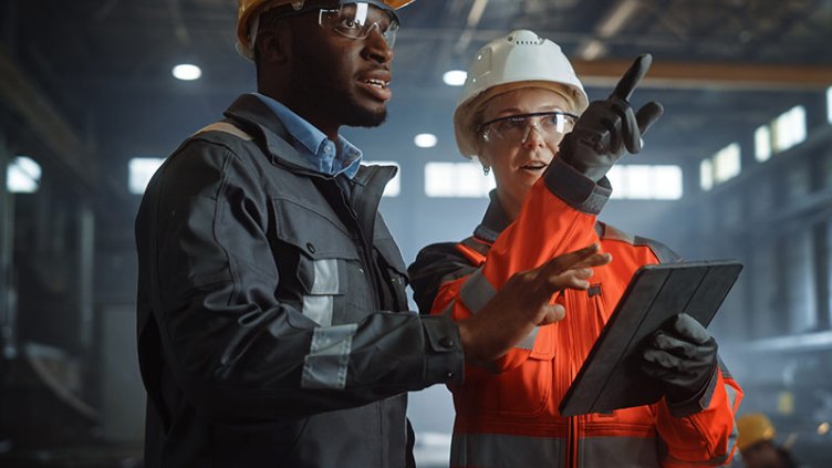 Two Heavy Industry Engineers Stand in Steel Metal Manufacturing Factory, Use Digital Tablet Computer and Have a Discussion