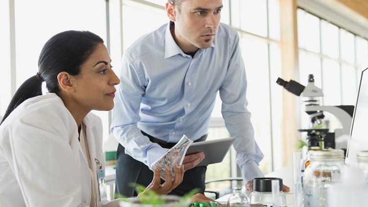 A woman holding a beaker working with a man in a life sciences space