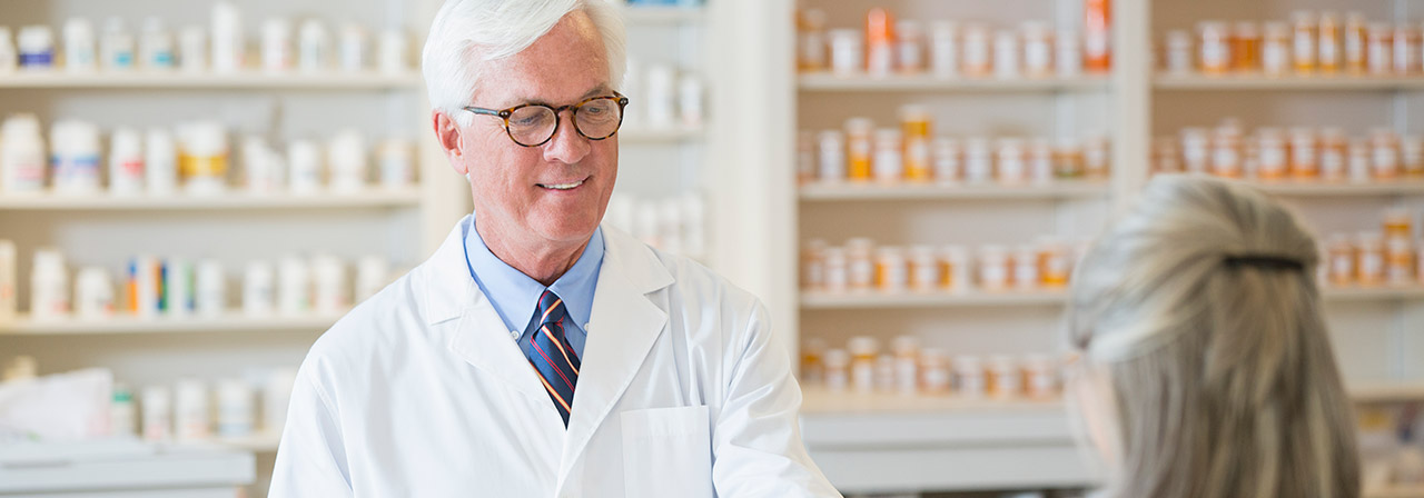 Caucasian pharmacist giving prescription to customer