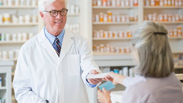 Caucasian pharmacist giving prescription to customer