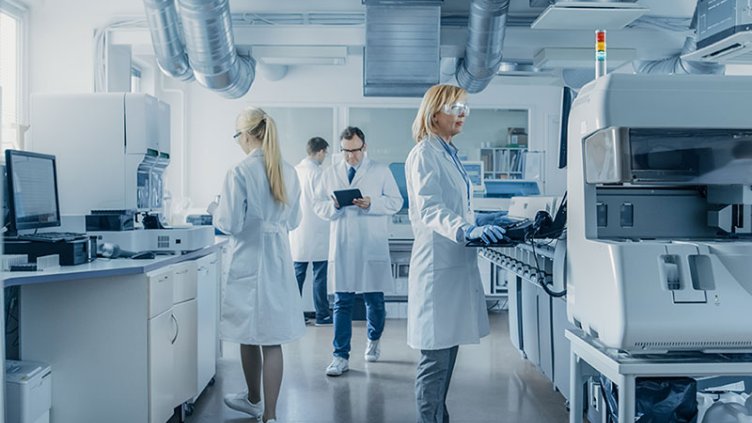 Group of engineers in white coats working in the laboratory of a pharmaceutical company