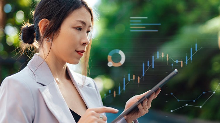 A businesswoman dressed in a suit is holding a tablet, symbolizing professionalism and technological engagement.