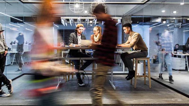 Group of young freelancers working on wireless technology at casual office.