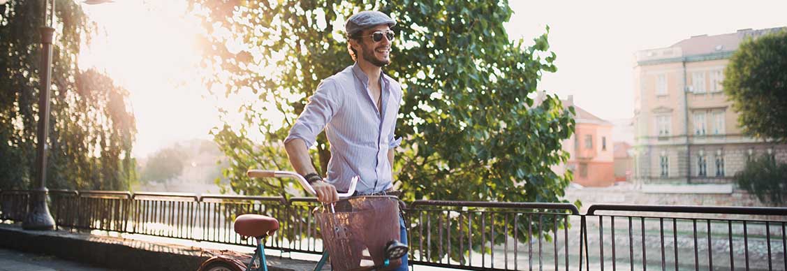 A man rides his bicycle along a sidewalk, enjoying a leisurely outdoor experience.