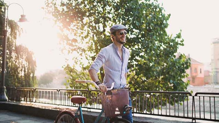 A man rides his bicycle along a sidewalk, enjoying a leisurely outdoor experience.