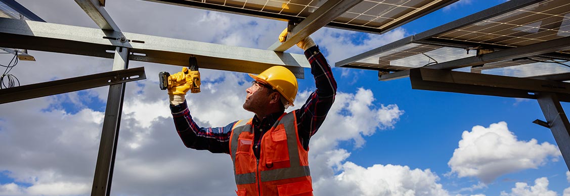 Worker using a power drill to work on a solar panel