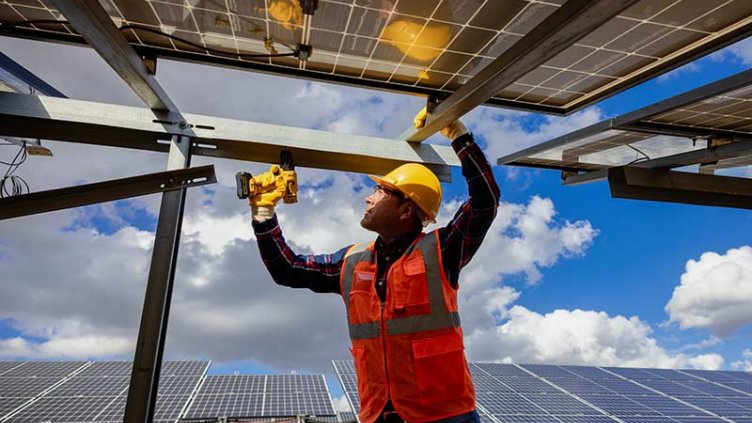 Worker using a power drill to work on a solar panel