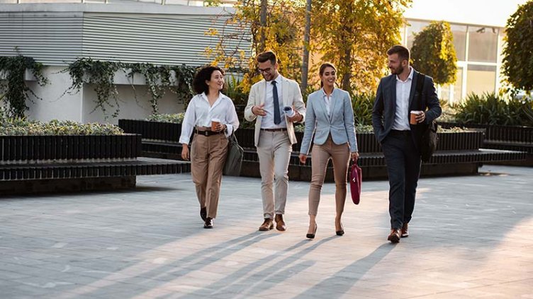 Group of business people walking outside in front of office buildings.