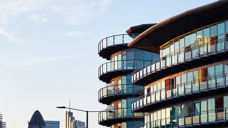 A building showcasing a generous balcony, accompanied by a tall building in the distance.