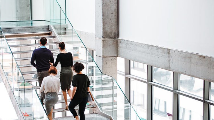 Rear view of group of young businesspeople walking up the stairs.