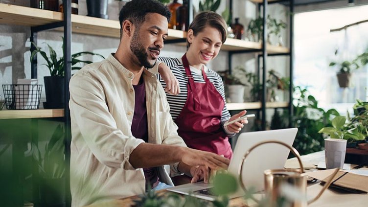 Shop assistants with laptop working in potted plant store, small business concept.