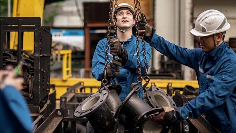 Two blue collar workers working in steel factory